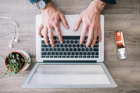 A man's hands typing on a laptop.