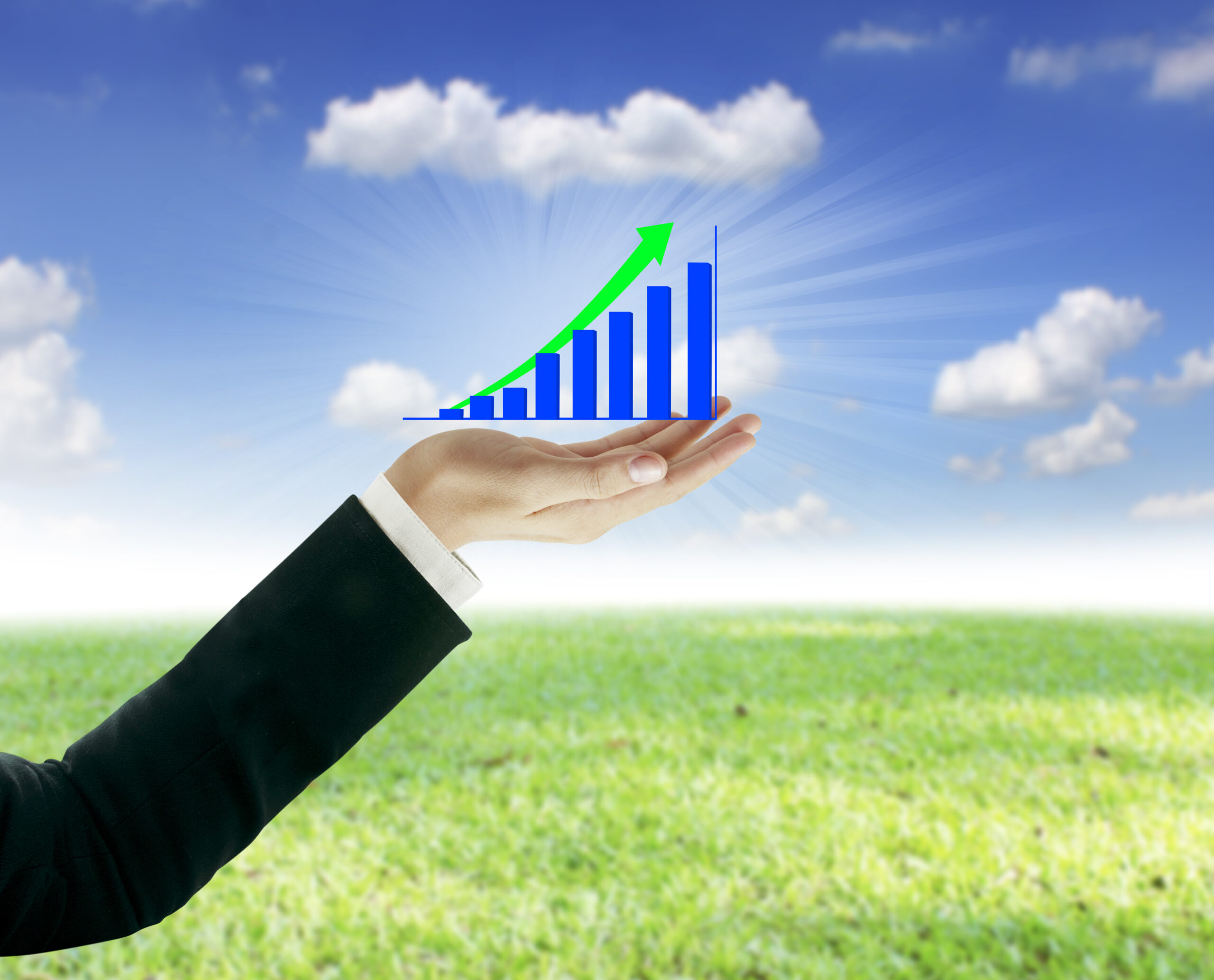 Hand holding rising bar graph with upward arrow representing business growth outdoors