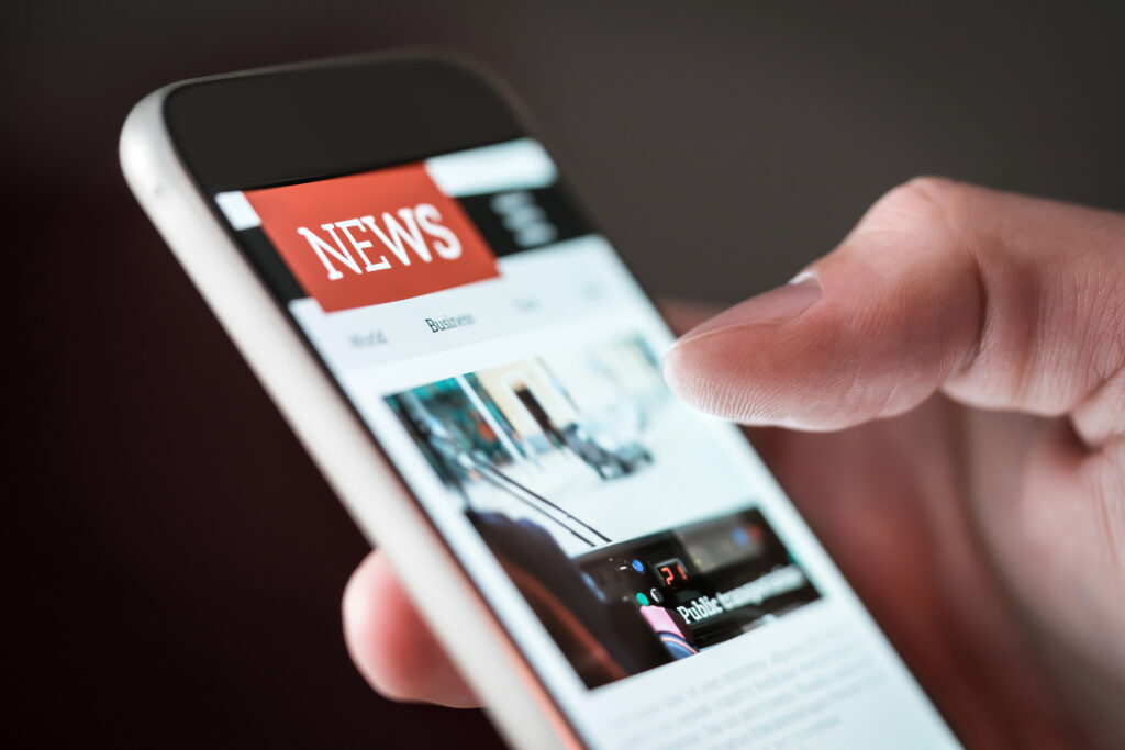 A mobile phone with a news site open on the screen